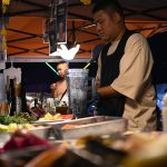 A vendor preparing fresh fruit drinks at a market stall