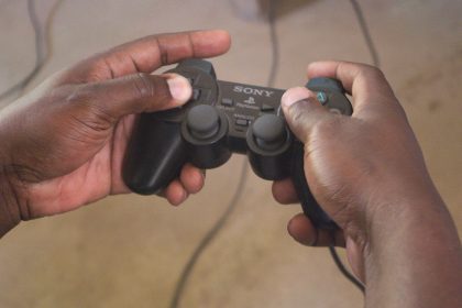 Hands holding a Sony PlayStation controller while playing a game