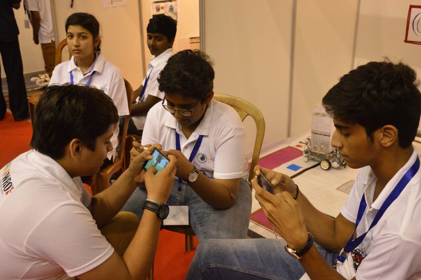 Students playing a mobile game together outdoors